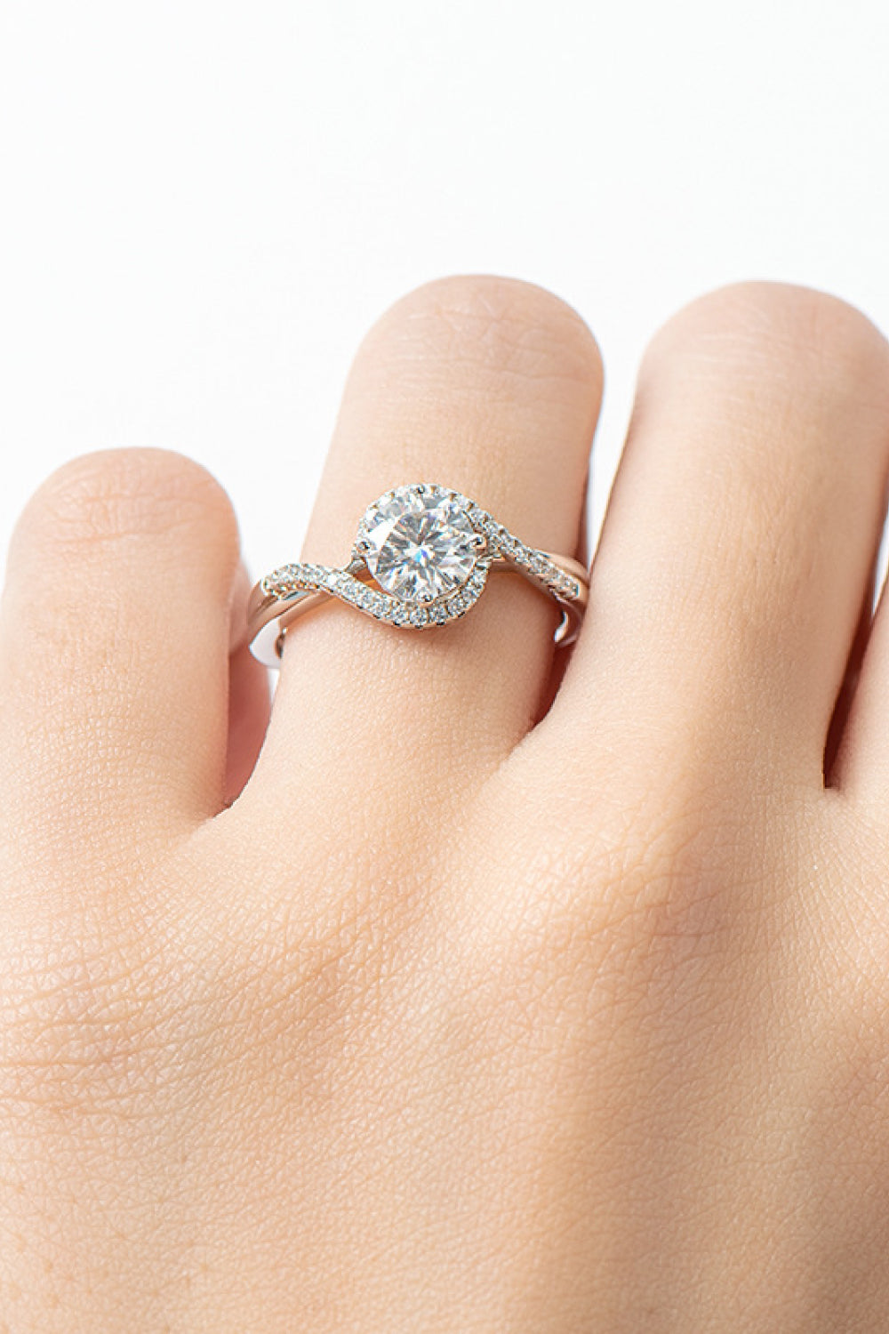 woman's twist style one carat moissonite platinum plated wedding ring on woman's finger